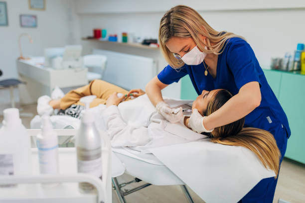 At her ordination professional beautician, doing the botox procedure on her female client face, to fill the gaps and lift a skin